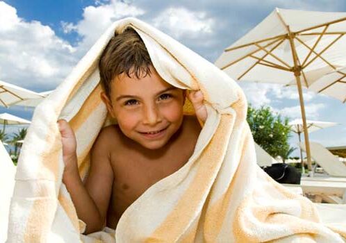 Child under towel at a sunny beach