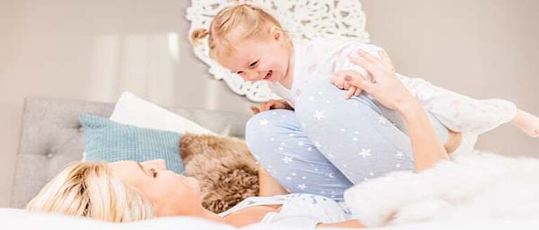 Mom and child wearing pajamas on bed