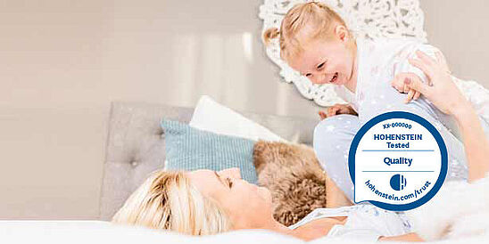 Mom and child on bed, Hohenstein Quality Label