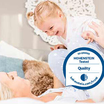 Mom and child on bed, Hohenstein Quality Label