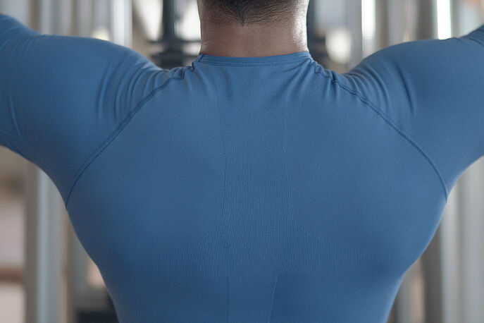 Man wearing blue shirt lifting weights in gym