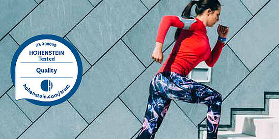 Woman running in performance gear, plus the Hohenstein Quality Label