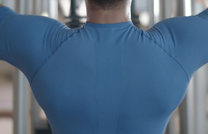 Man wearing blue shirt lifting weights in gym