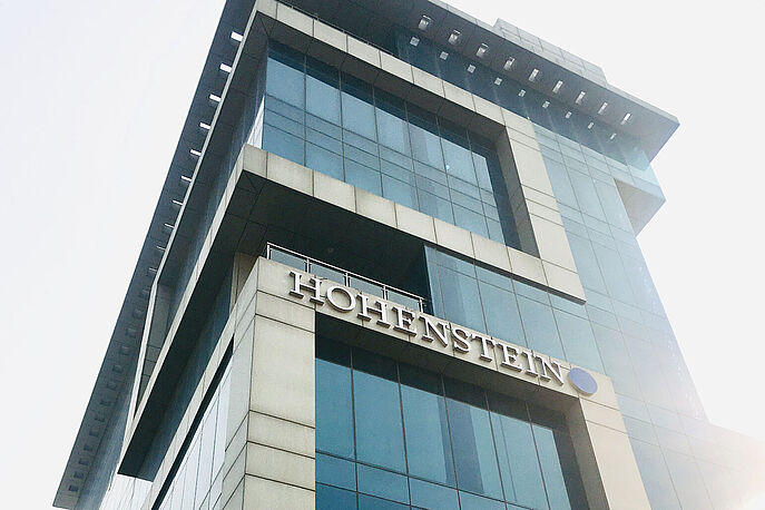 Hohenstein Building in Gurugram, India sun shining behind tall building with Hohenstein logo