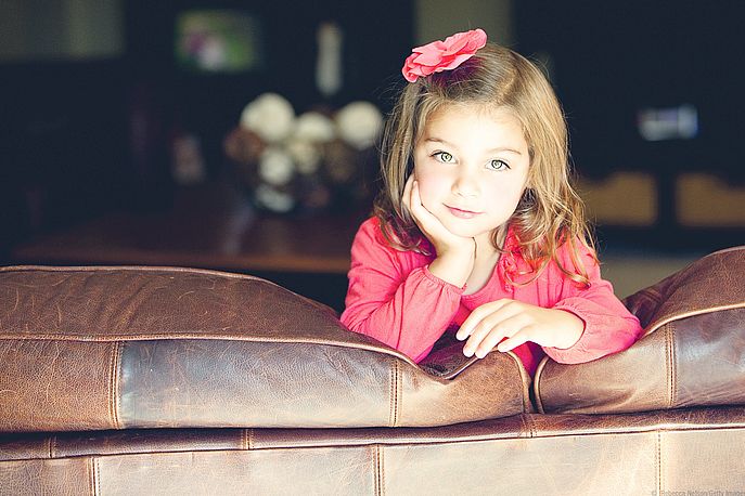 Girl leaning on brown leather couch