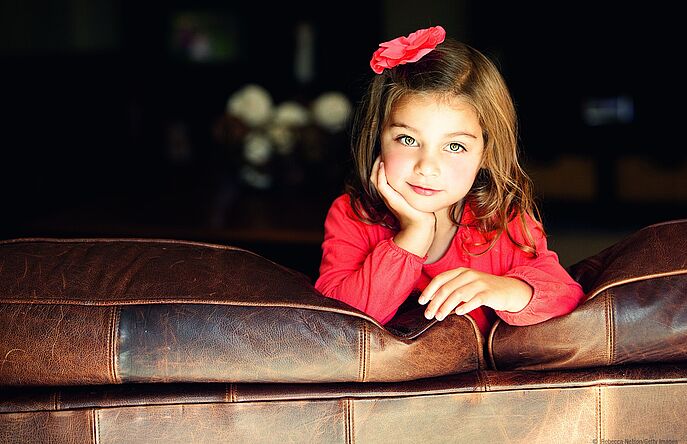 Girl leaning on brown leather couch