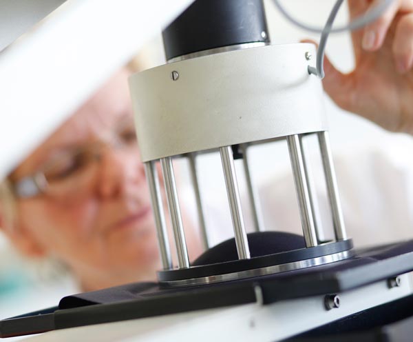 Lab technician performing physical strength test on surgical textile material