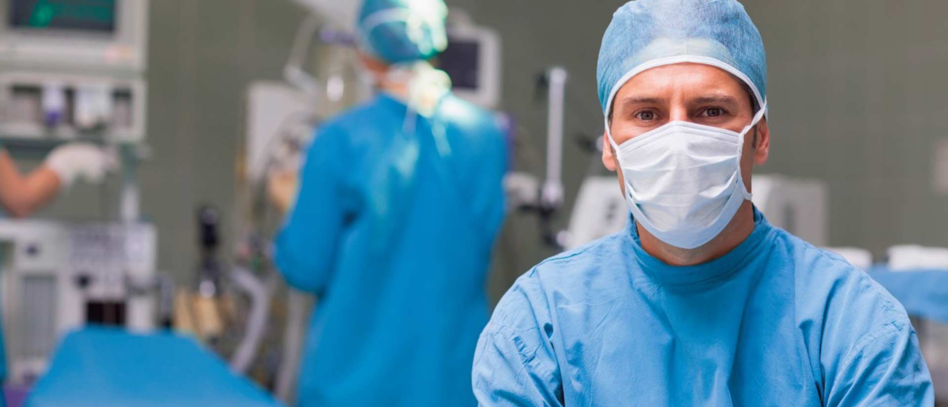 Surgeons in operating room wearing face masks and surgical gowns