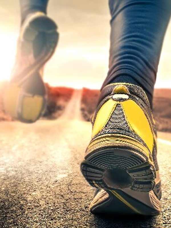 View from ground of person walking away wearing yellow athletic shoes