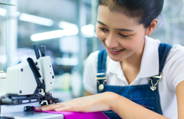 Textile worker at sewing machine in safe workplace