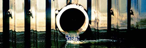 Wastewater flowing out of drainpipe into river