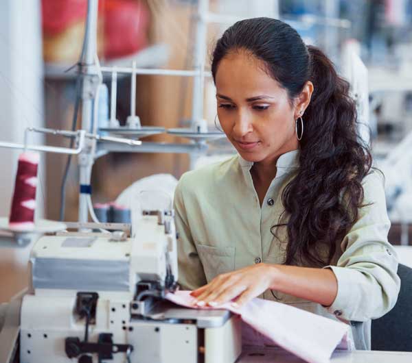 Textile worker in cut and sew factory sewing a garment