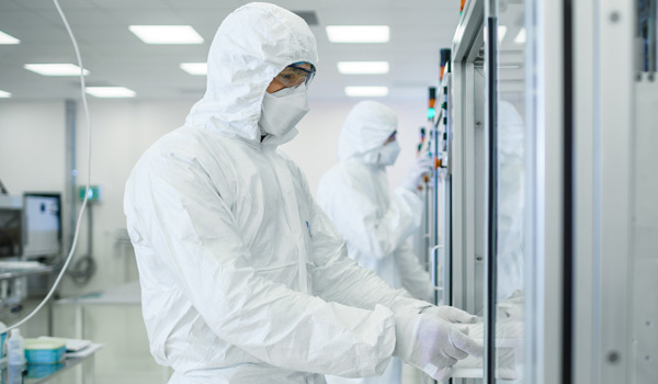 Techs in testing lab wearing cleanroom gear and FFP masks