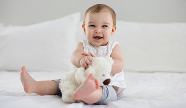 Baby holding stuffed animal on bed